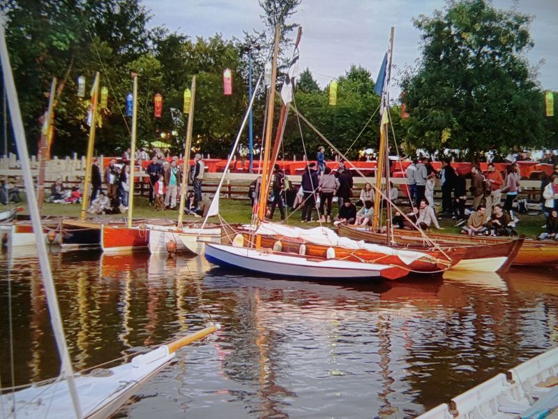 Plusieurs bateaux rangés dans le port ; le public au loin