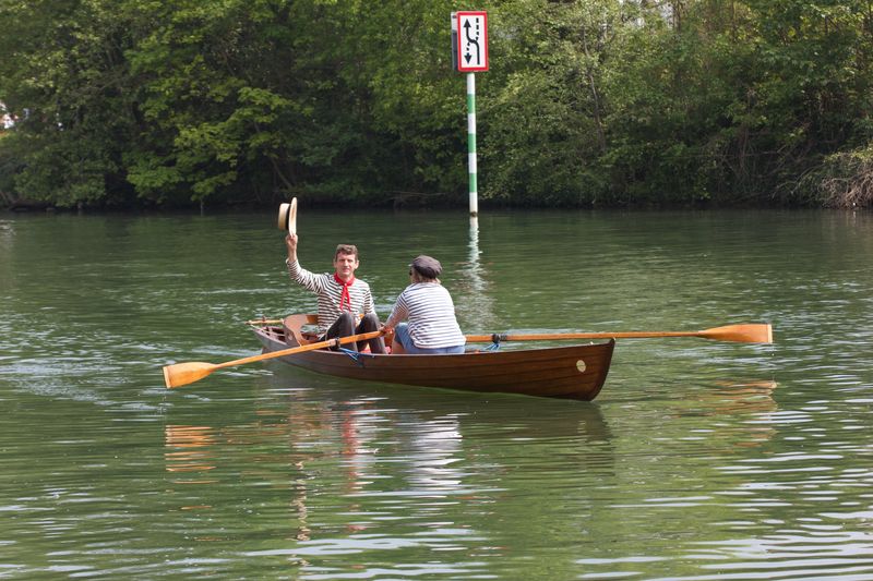La yole Lutin sur l'eau ; le barrreur salue, la rameuse lui fait face