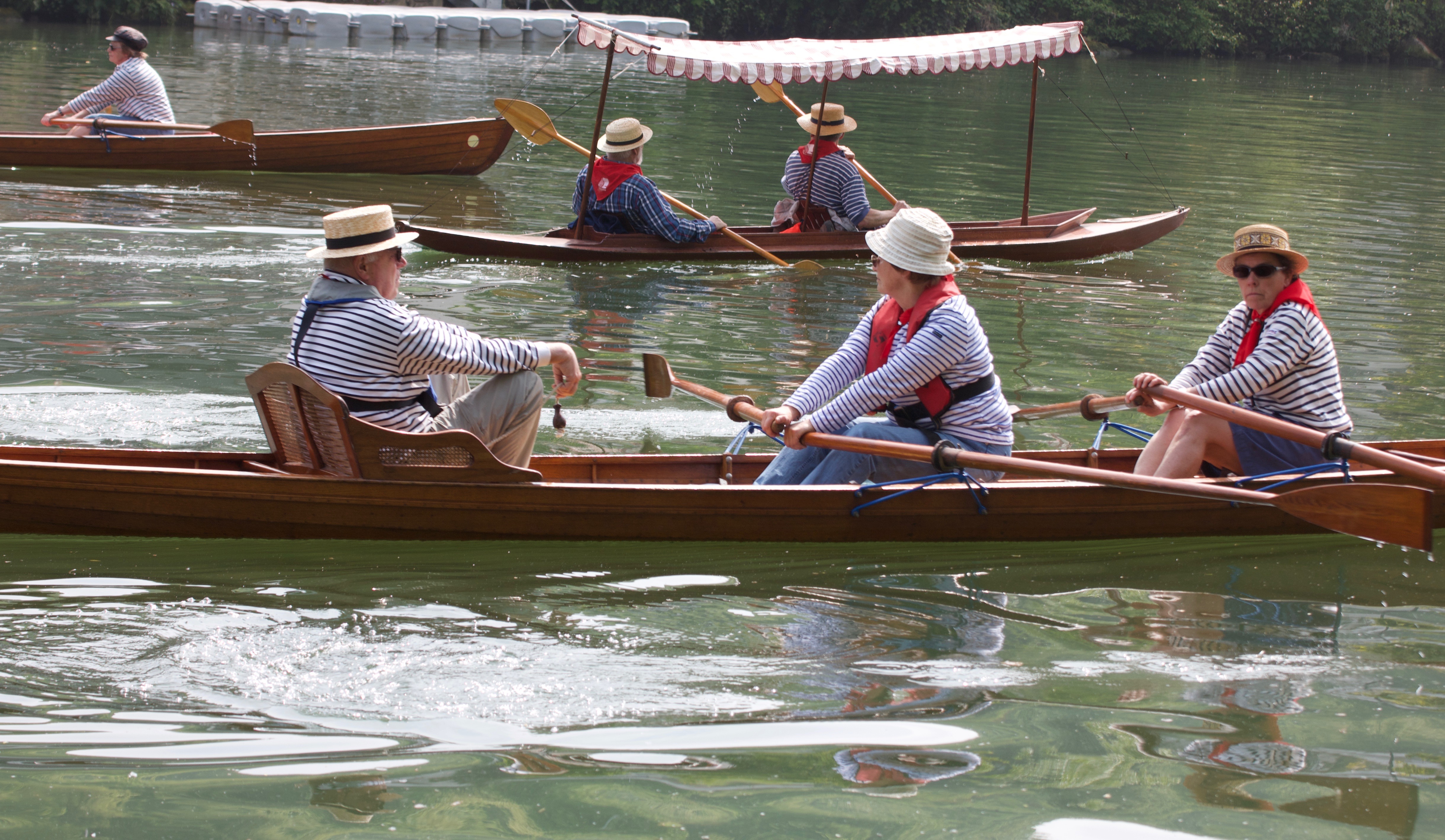 3 bateaux en bois à rames avec 2 ou 3 rameurs 